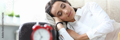 Fotomural Girl sleeps after work couch, table an alarm clock