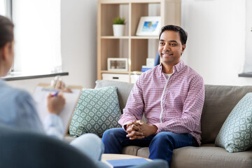 Wall Mural - psychology, mental therapy and people concept - happy smiling young indian man patient and woman psychologist at psychotherapy session