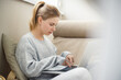 © snedorez - Side view of young blonde looking to side holding laptop in her hands sitting in armchair