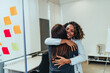 Excited business women hugging each other in modern office.
