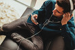 © carballo - young man on the sofa in the apartment with mobile phone and headphones