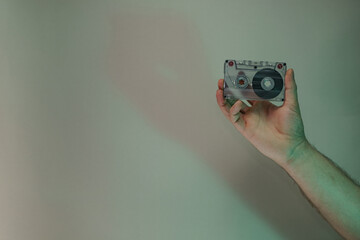 Poster - Hand holding audio cassette tape in the color light. Beautiful minimal in neon light. Minimalism retro style concept. Background pattern for design.