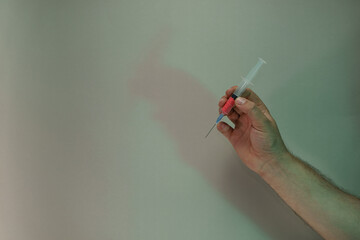 Poster - Hand holding creative syringe with red vaccine in the color light. Beautiful. minimal in neon light. Minimalism retro style concept. Background pattern for design.