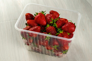 Wall Mural - a clear plastic container with ripe juicy red strawberries is on table