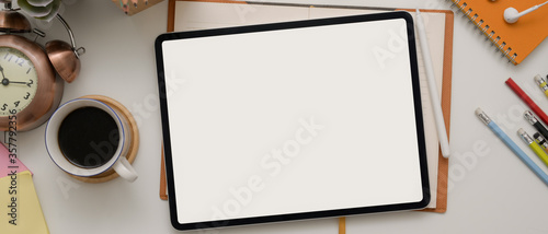 Fotomural Top view of worktable with blank screen tablet above schedule book with coffee c