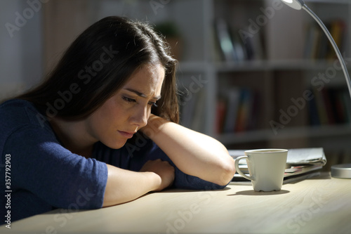 Fotomural Sad woman complains sitting on a desk at night at home