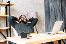 Take A Break On A Workplace. A Young African-American Guy Leaned Back In His Chair Relaxed, He Is Pleased With The Work Done