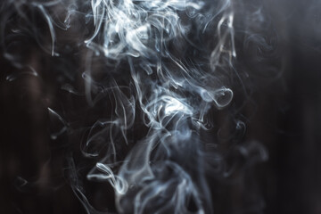 Image of backlit puffs of smoke, on a dark background.