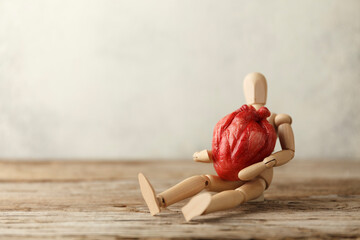 Wall Mural - Wooden toy man holds a heart. Donor and transplant, symptoms of an attack. Surgical Assistance