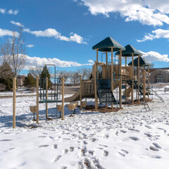 Wall Mural - Square Park playground amid footprints on sunlit snow covering the ground in winter