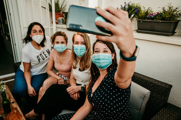 .Group of young girlfriends meeting after the quarantine caused by the covid pandemic19. Taking precaution with the use of surgical masks and taking the first photos together with a smartphone.