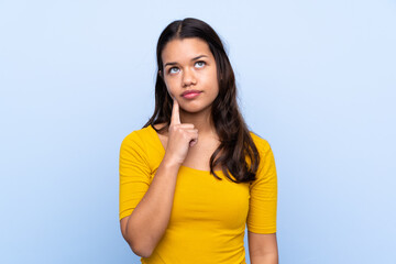 Young Colombian girl over isolated blue background thinking an idea