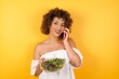 © Jihan - Portrait of a smiling young casual brunette woman  holding a salad talking on mobile phone isolated over white background.