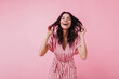 © Look! - Blithesome caucasian lady playing with her wavy hair on pink background. Ecstatic slim woman having fun in studio