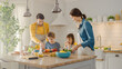 In Kitchen: Family of Four Cooking Together Healthy Dinner. Mother, Father, Little Boy and Girl, Preparing Salads, Washing and Cutting Vegetables. Cute Children Helping their Beautiful Caring Parents