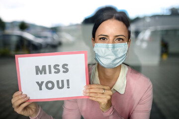 Poster - Portrait of teacher with face mask after lockdown, holding miss you sign.