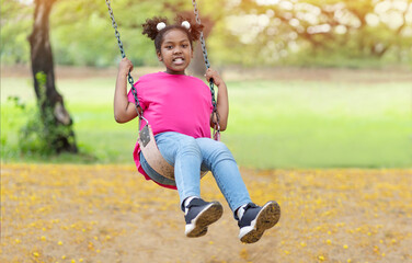 Wall Mural - Cute African American little girl playing on swing. Smiling child playing in summer in the park. Kid in the field trips outdoor, Freedom, Happy lifestyle, Summer outdoor.