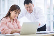 © FILEOPEN CREATION - Two Asian business men and women looking at the laptop and talking about work projects at office.