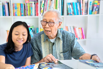 Wall Mural - Old man help his granddaughter to study in library