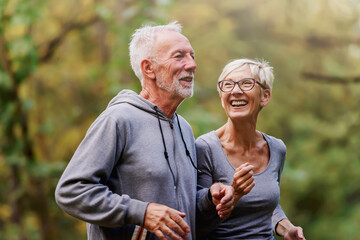 Wall Mural - Smiling senior couple jogging in the park