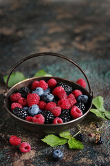 Wall Mural - Berries raspberries, blueberries and blackberries in a silver basket on an old background. Place for text. Copy space.