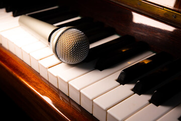 Microphone lying on the piano keyboards. Free time activities at home. Karaoke hobby. Creating music.