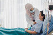 Young Asian woman Muslim doctor giving advice discussion and check up to elderly patient sitting in bed at hospital which smiling and felling happy. Medicine and health care safe concept.