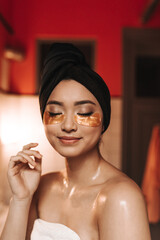 Wall Mural - Portrait of woman after shower in towels. Girl does facial treatments and poses in patches