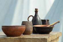 Folk Utensil Bowls Mugs Of Clay Bottles On A Wooden Table Outdoors