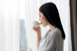 © Chanakon - Young beautiful woman enjoy drinking with cup of coffee or tea near the window.