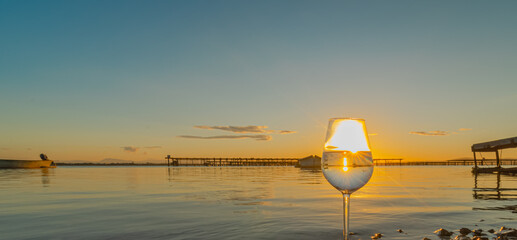 Wall Mural - Verre à vin avec reflets d'un coucher de soleil sur la mer.