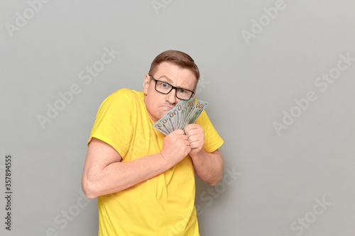 Fotomural Portrait of funny greedy man holding money in hands