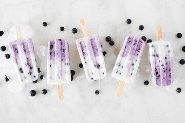 Poster - Group of blueberry vanilla yogurt ice pops. Above view in a row on a white marble background.