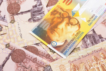 Wall Mural - A yellow, ten Swiss franc note from Switzerland close up in macro with Egyptian one pound bank notes