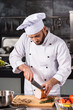 © stockbusters - Chef cut meat at kitchen. Chef male slice hum at professional kitchen.