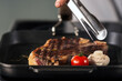 © stockbusters - Grill steak at griddle pan. Closeup frying fork with grill beef.