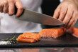 © stockbusters - Chef hands cutting fish fillet. Closeup male hands slicing salmon.