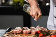 © stockbusters - Chef hands spray meat at kitchen restaurant. Closeup chef hands pour beef.
