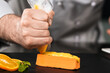 © stockbusters - Chef man cook cake at kitchen restaurant. Closeup chef hand cook orange cake.