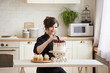 © MestoSveta - Young professional confectioner happy with her work, carefully corrects the berries on the cake, looking at camera. Lifestyle cooking concept, copy space. Work at home concept