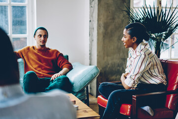 Wall Mural - Smiling black woman listening to friends during meeting