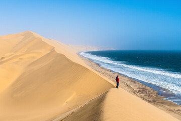 Tourist admiring the view from a sand dune at Sandwich Harbour