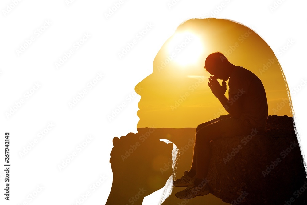 Young man pray outdoor on top of mountains in the sunset - obrazy, fototapety, plakaty 
