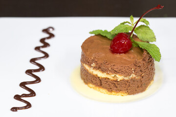 dessert of black chocolate mousse with white chocolate sauce and cherry