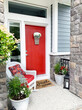 Bright orange front door and porch with a wicker chair. Colorful entrance.