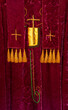 Red vestments for Christian worship celebrations, feast days. Liturgical vintage garment and stole hanging for display. Closeup shows gold thread crosses & tassels all made in France.