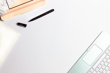 Wall Mural - High angle shot of a laptop keyboard and a notebook with a black pen on a white surface