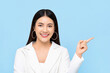 © Atstock Productions - Pretty Asian woman in white suit smiling and pointing finger to space aside isolated on light blue background