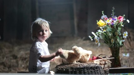 Poster - Little toddler blond boy, reading a book in the attic, nice atmosphere, flowers and strawberries next to him