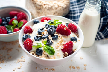 Breakfast, oatmeal with blueberry and raspberry on white bowl in the morning.